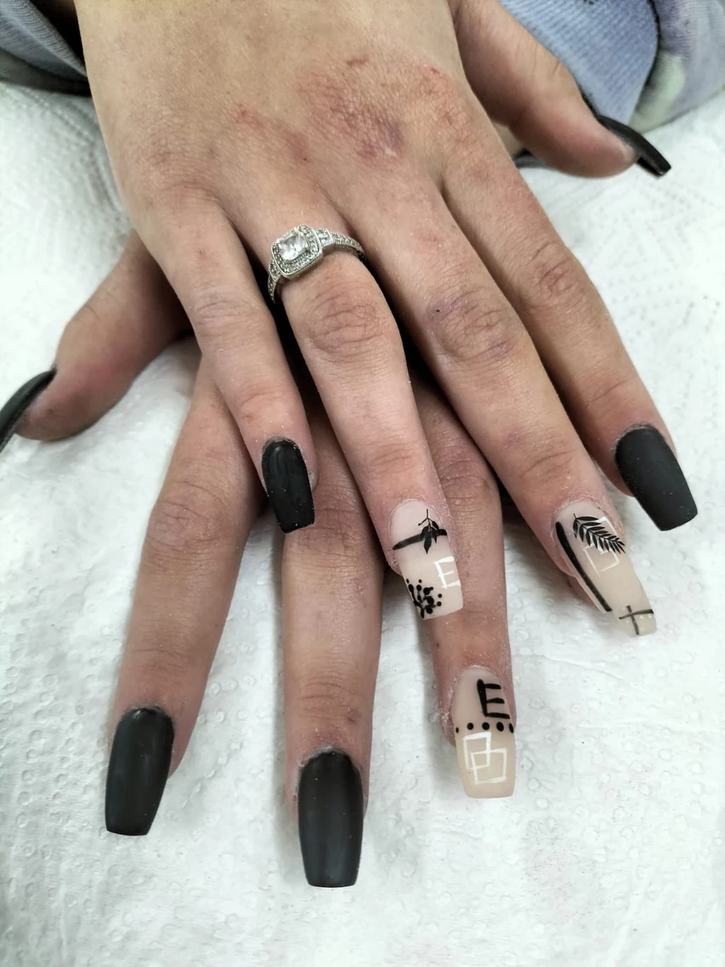 Matte black coffin nails with fine line art on a nude accent